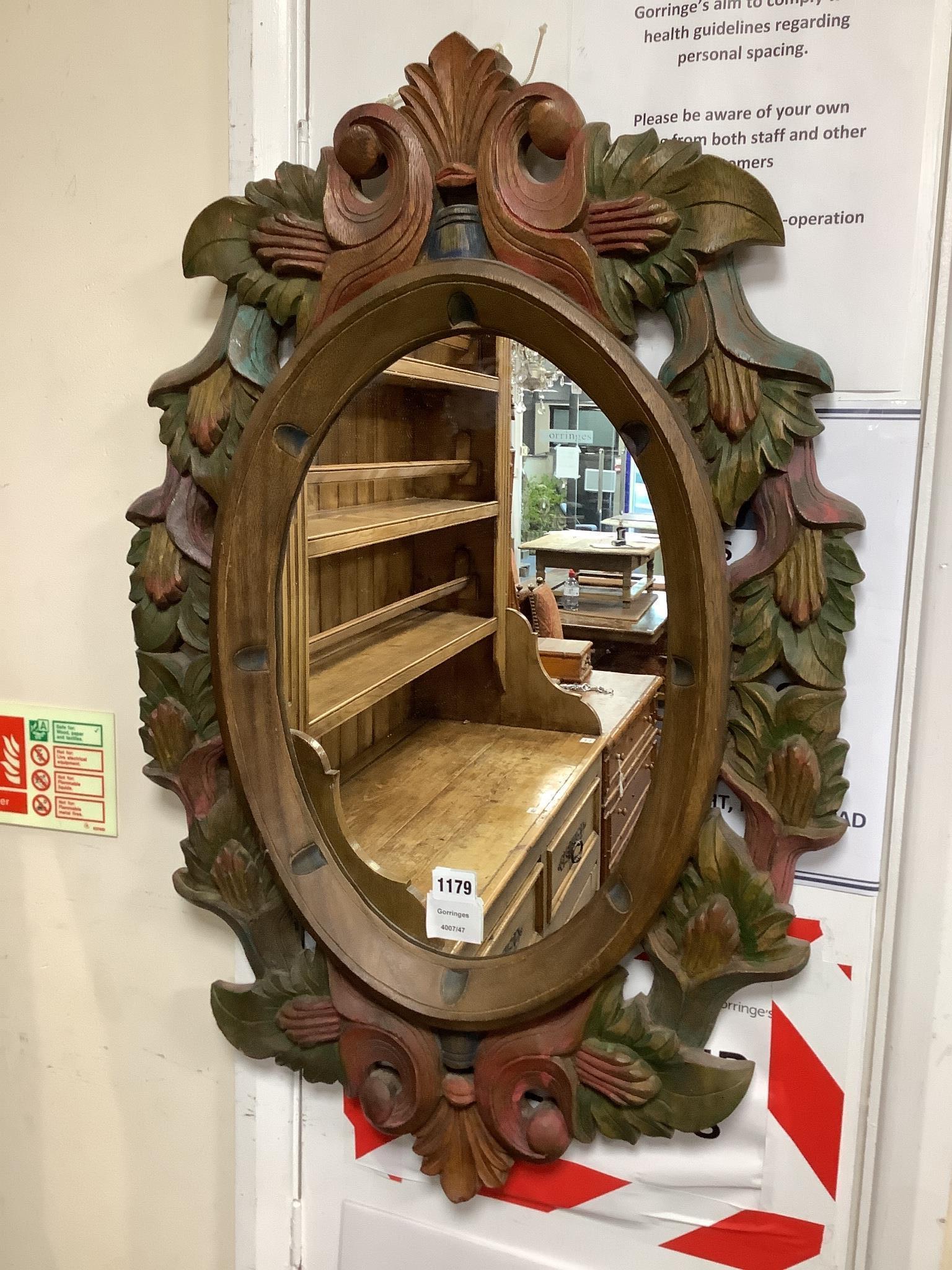 A Victorian style oval polychrome carved wood mirror width 50 cms, height 78 cms